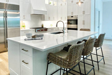 Inspiration for a large coastal l-shaped vinyl floor and beige floor open concept kitchen remodel in Miami with an undermount sink, shaker cabinets, white cabinets, quartz countertops, white backsplash, quartz backsplash, stainless steel appliances, an island and white countertops