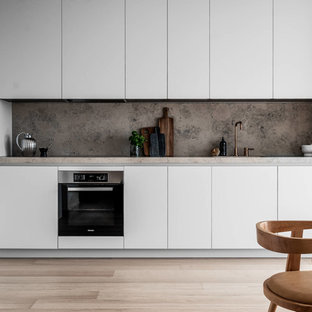 Idéer för att renovera ett funkis grå grått kök, med släta luckor, vita skåp, grått stänkskydd, stänkskydd i sten, ljust trägolv och beiget golv