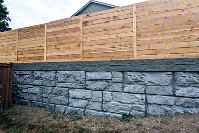 Photo of a huge traditional full sun backyard concrete paver and wood fence retaining wall landscape for summer.