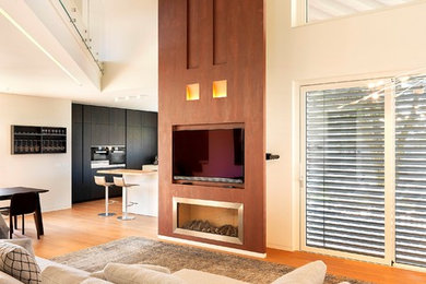 Photo of a large contemporary open concept living room in Other with white walls, light hardwood floors, a hanging fireplace, a metal fireplace surround and a wall-mounted tv.