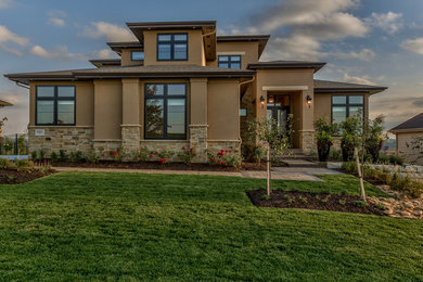 Example of a large transitional brown two-story stucco house exterior design in Omaha with a hip roof and a shingle roof