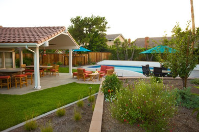 Large transitional backyard full sun garden in Orange County with a fire feature and concrete pavers for summer.