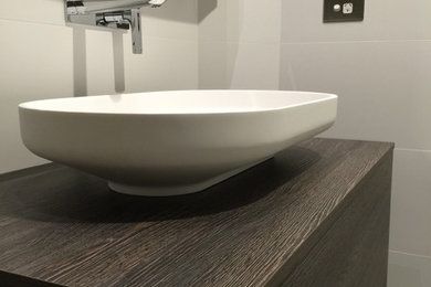 Photo of a small contemporary bathroom in Perth with dark wood cabinets, wood benchtops and porcelain floors.