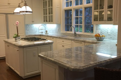 Example of a large classic u-shaped dark wood floor open concept kitchen design in San Francisco with raised-panel cabinets, white cabinets, granite countertops, mosaic tile backsplash, an island, an undermount sink, gray backsplash and stainless steel appliances