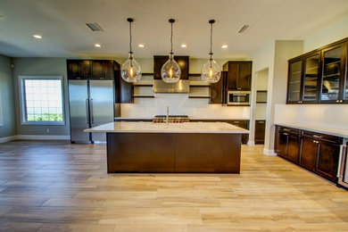 Example of a large transitional l-shaped light wood floor eat-in kitchen design in Los Angeles with a farmhouse sink, shaker cabinets, medium tone wood cabinets, marble countertops, white backsplash, subway tile backsplash, stainless steel appliances and an island