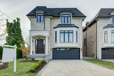 Photo of a mid-sized transitional two-storey beige house exterior in Toronto with stone veneer, a hip roof and a shingle roof.