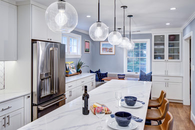 Eat-in kitchen - transitional l-shaped medium tone wood floor eat-in kitchen idea in DC Metro with a farmhouse sink, shaker cabinets, white cabinets, quartz countertops, white backsplash, subway tile backsplash, stainless steel appliances and an island