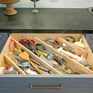 Inspiration pour une grande arrière-cuisine urbaine en L avec un évier 1 bac, un placard à porte plane, des portes de placard en bois clair, une crédence blanche, une crédence en carreau de verre, un électroménager en acier inoxydable, un sol en bois brun et un îlot central.