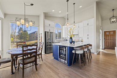 Example of a classic l-shaped light wood floor and brown floor kitchen design in Denver with an undermount sink, shaker cabinets, granite countertops, gray backsplash, stainless steel appliances and an island