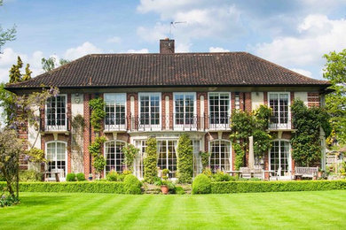 Inspiration for a red classic two floor brick house exterior in Surrey with a hip roof.