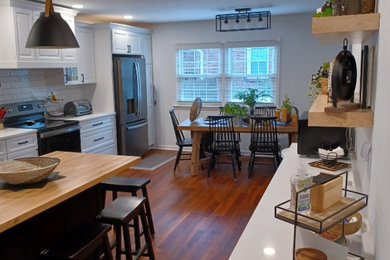 Inspiration for a large transitional single-wall vinyl floor and brown floor eat-in kitchen remodel in Louisville with an undermount sink, raised-panel cabinets, white cabinets, quartz countertops, white backsplash, subway tile backsplash, stainless steel appliances, an island and white countertops