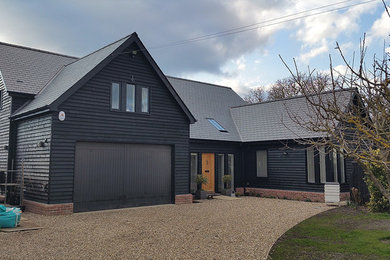 Large traditional two-storey black exterior in London with wood siding and a gable roof.