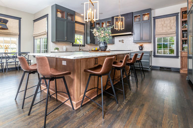 Example of a mid-sized minimalist dark wood floor and brown floor eat-in kitchen design in Charlotte with a drop-in sink, glass-front cabinets, blue cabinets, quartzite countertops, white backsplash, subway tile backsplash, paneled appliances, an island and white countertops