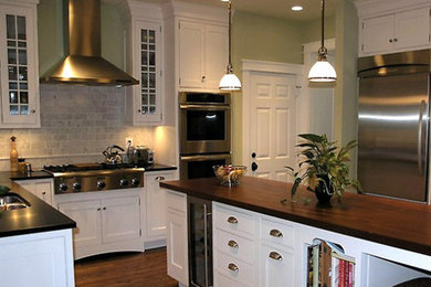 Large elegant u-shaped medium tone wood floor and brown floor enclosed kitchen photo in Austin with a double-bowl sink, recessed-panel cabinets, white cabinets, gray backsplash, stainless steel appliances, an island, granite countertops and subway tile backsplash