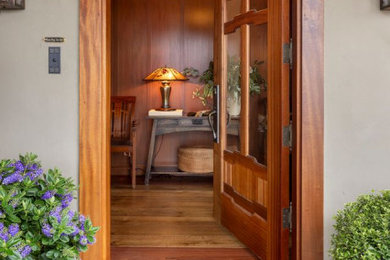 Example of an arts and crafts medium tone wood floor, wall paneling and wood ceiling entryway design in Other with a medium wood front door