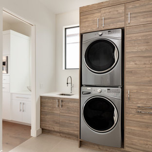 Immagine di una lavanderia multiuso moderna di medie dimensioni con lavello sottopiano, ante lisce, ante in legno scuro, top in quarzo composito, lavatrice e asciugatrice a colonna e top bianco