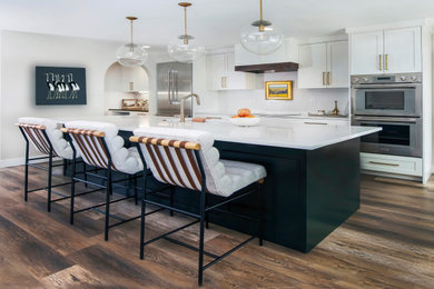 Inspiration for a mid-sized transitional single-wall dark wood floor and brown floor eat-in kitchen remodel in Denver with an undermount sink, raised-panel cabinets, white cabinets, quartzite countertops, white backsplash, stainless steel appliances, an island and white countertops