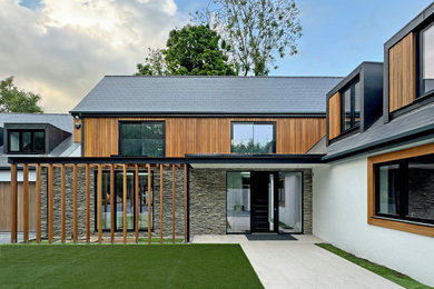 Design ideas for a large contemporary front house exterior in Surrey with a pitched roof, a tiled roof and a grey roof.
