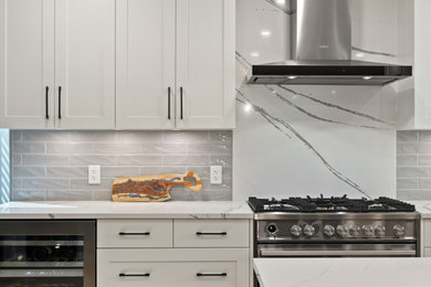 Inspiration for a mid-sized contemporary l-shaped medium tone wood floor and brown floor eat-in kitchen remodel in Calgary with an undermount sink, recessed-panel cabinets, white cabinets, quartz countertops, gray backsplash, subway tile backsplash, stainless steel appliances, an island and white countertops