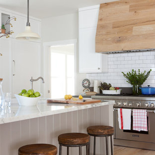 Imagen de cocina en L, campestre, grande, abierta, con fregadero sobremueble, armarios estilo shaker, puertas de armario blancas, encimera de mármol, salpicadero blanco, electrodomésticos de acero inoxidable, suelo de madera en tonos medios, una isla y salpicadero de azulejos tipo metro