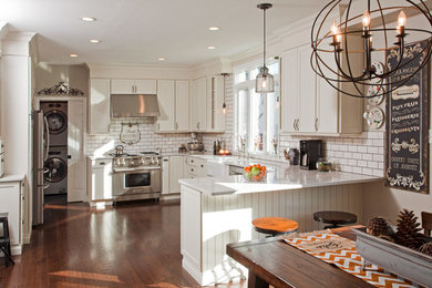 Transitional u-shaped dark wood floor kitchen photo in Philadelphia with a farmhouse sink, recessed-panel cabinets, white cabinets, white backsplash, subway tile backsplash, stainless steel appliances and a peninsula