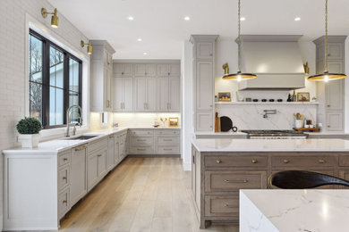 Inspiration for a transitional l-shaped light wood floor and beige floor kitchen remodel in Minneapolis with an undermount sink, shaker cabinets, gray cabinets, white backsplash, stone slab backsplash, stainless steel appliances, two islands and white countertops