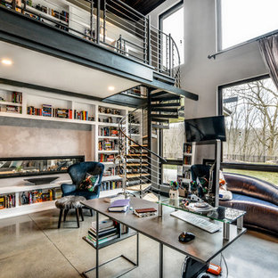 Large contemporary home office in Other with a library, beige walls, concrete floors, a two-sided fireplace, a concrete fireplace surround, a freestanding desk and beige floor.
