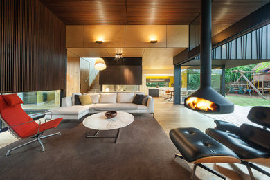 Photo of a contemporary open concept living room in Melbourne with light hardwood floors and a hanging fireplace.