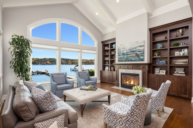 Living room - large coastal open concept medium tone wood floor and brown floor living room idea in Seattle with gray walls, a stone fireplace and a concealed tv