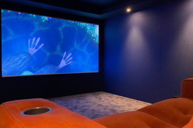 Diseño de cine en casa moderno pequeño con paredes azules, moqueta, pantalla de proyección y suelo gris