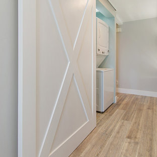 Medium sized nautical single-wall laundry cupboard in San Diego with shaker cabinets, light wood cabinets, quartz worktops, green walls, vinyl flooring, a stacked washer and dryer, grey floors and green worktops.
