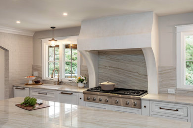 Example of a mid-sized beach style u-shaped medium tone wood floor, brown floor and tray ceiling eat-in kitchen design in Denver with a drop-in sink, flat-panel cabinets, white cabinets, white backsplash, stainless steel appliances, an island and white countertops