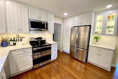 Cette photo montre une cuisine chic de taille moyenne avec un placard à porte shaker, des portes de placard blanches et un plan de travail en quartz modifié.