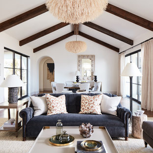 Modelo de salón para visitas abierto, mediterráneo, de tamaño medio, con paredes blancas, suelo de madera en tonos medios, chimenea tradicional, marco de chimenea de yeso y suelo blanco