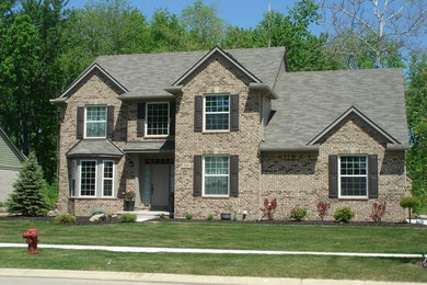 Large traditional gray two-story stone exterior home idea in Detroit