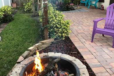 Mid-sized transitional backyard brick patio photo in Tampa with a fire pit and no cover