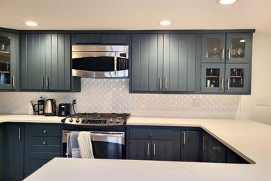 Example of a mid-sized minimalist u-shaped vinyl floor and brown floor eat-in kitchen design in Other with an undermount sink, flat-panel cabinets, gray cabinets, quartz countertops, white backsplash, ceramic backsplash, stainless steel appliances, a peninsula and white countertops