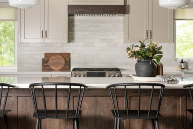 Inspiration for a large timeless l-shaped medium tone wood floor and brown floor kitchen pantry remodel in Salt Lake City with a farmhouse sink, flat-panel cabinets, medium tone wood cabinets, quartz countertops, white backsplash, subway tile backsplash, stainless steel appliances, an island and multicolored countertops