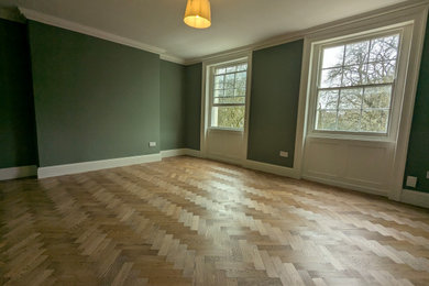 Inspiration for a medium sized victorian bedroom in London with green walls and light hardwood flooring.
