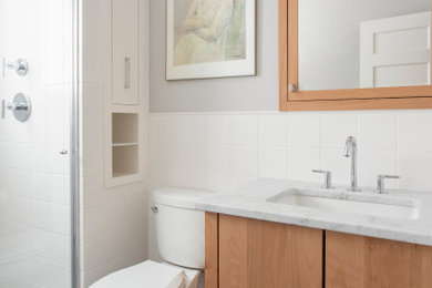 Bathroom - mid-sized modern 3/4 white tile and ceramic tile black floor and single-sink bathroom idea in Minneapolis with flat-panel cabinets, light wood cabinets, a one-piece toilet, white walls, a drop-in sink, marble countertops, white countertops and a built-in vanity