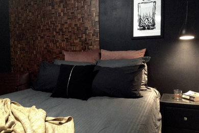 Photo of a small industrial guest bedroom in Other with black walls, light hardwood floors, brown floor and decorative wall panelling.