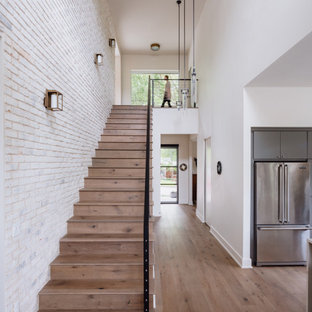 Idée de décoration pour un petit escalier droit design avec des marches en bois, des contremarches en bois, un garde-corps en métal et un mur en parement de brique.