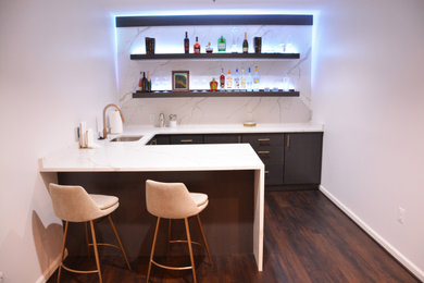 Example of a mid-sized trendy u-shaped dark wood floor and brown floor seated home bar design in DC Metro with an undermount sink, flat-panel cabinets, dark wood cabinets, quartz countertops, white backsplash, quartz backsplash and white countertops