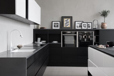 Inspiration för ett stort skandinaviskt grå grått kök, med en nedsänkt diskho, släta luckor, svarta skåp, bänkskiva i koppar, svarta vitvaror, betonggolv, en köksö och grått golv