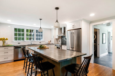 Mid-sized transitional l-shaped light wood floor eat-in kitchen photo in Boston with an undermount sink, shaker cabinets, white cabinets, soapstone countertops, white backsplash, subway tile backsplash, stainless steel appliances, an island and gray countertops