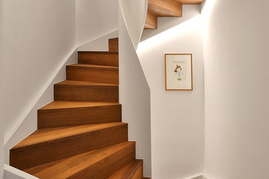 Photo of a small contemporary wood curved staircase in Munich with wood risers and wood railing.