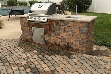Photo of a mid-sized traditional backyard patio in New York with an outdoor kitchen, brick pavers and no cover.