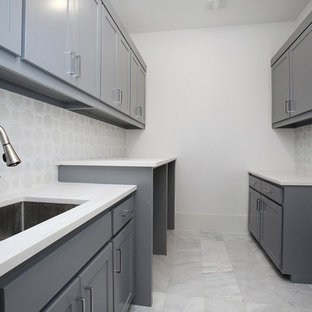 This is an example of a large traditional galley utility room in Dallas with a submerged sink, shaker cabinets, grey cabinets, engineered stone countertops, white walls, marble flooring, an integrated washer and dryer, white floors and white worktops.