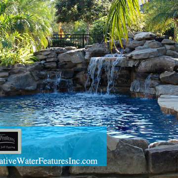 Tropical backyard room with pool waterfall, fireplace, and koi pond