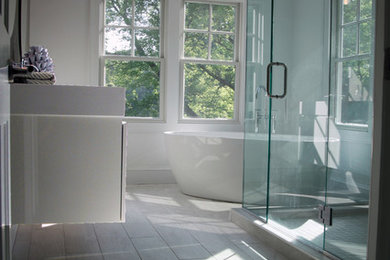 Design ideas for a mid-sized modern master bathroom in Bridgeport with flat-panel cabinets, a freestanding tub, a corner shower, gray tile, porcelain tile, white walls, porcelain floors, an integrated sink, grey floor and a hinged shower door.